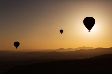 Arka planda gündoğumu olan balonların silueti, hava manzarası