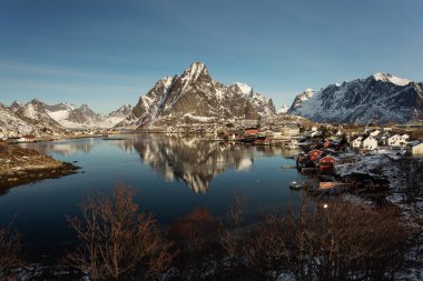 Kışın güzel Sacrisoya köyü manzarası. Arka planda gündoğumuyla birlikte anıtlar. Lofoten, Norveç.