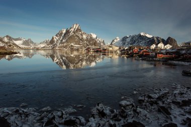 Kışın güzel Sacrisoya köyü manzarası. Arka planda gündoğumuyla birlikte anıtlar. Lofoten, Norveç.