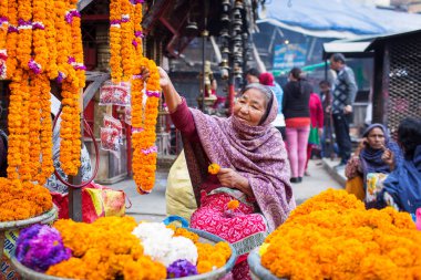 DURBAR KARAK, KATHMANDU, NEPAL - 10 Kasım 2017: Nepal, Kathmandu 'daki sokak pazarında dua için çiçek çelengi satan kadın