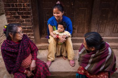 Bhaktapur, Nepal - 11 Kasım 2017. Nepal, Bhaktapur sokaklarında kızıyla rahatlayan bir kadın..