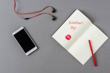 gri yüzeyüzerinde sevgililer günü kelimeleri ile akıllı telefon ve dizüstü üst görünümü