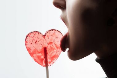 beyaz izole kalp şeklinde lolipop yalama kadın kırpılmış görüntü, sevgililer günü kavramı