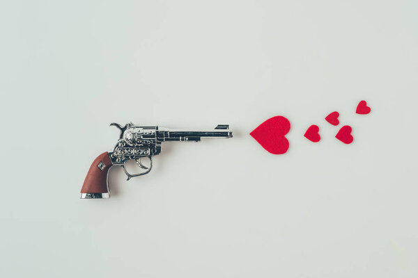 top view of gun aiming at paper hearts isolated on white, valentines day concept