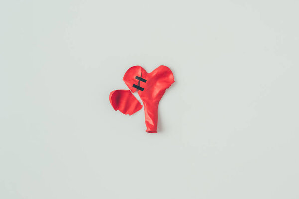 top view of broken heart shaped balloon with insulating tape isolated on white, valentines day concept 