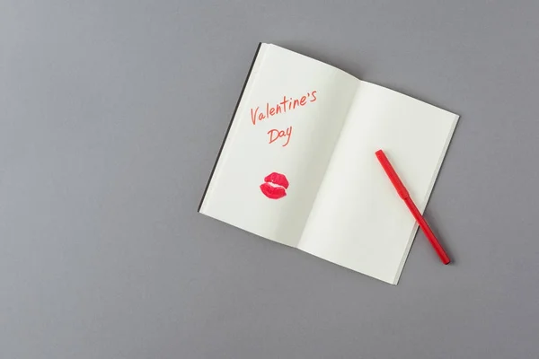 言葉バレンタインデーと灰色の表面に唇のプリントとオープンノートブックのトップビュー — ストック写真