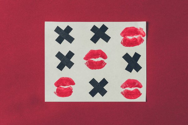 top view of tic-tac-toe with black crosses and lips prints isolated on red, valentines day concept
