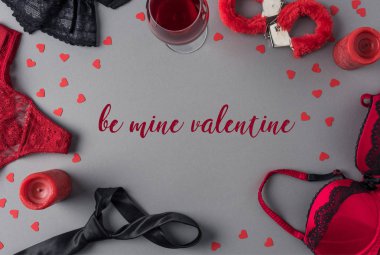 Top view of words be mine valentine between underwear and glass of wine clipart