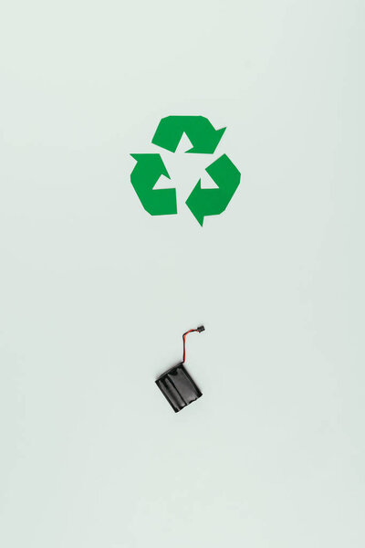 верхний вид знака вторичной переработки и аккумулятора, изолированных на сером
