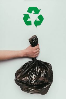 cropped shot of woman holding garbage bag in hand with recycle sign isolated on grey clipart