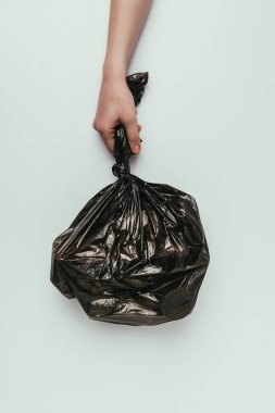 cropped shot of woman holding garbage bag in hand isolated on grey clipart