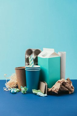 close up view of arranged cardboard and paper disposable garbage on blue background clipart