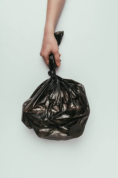 обрезанный снимок женщины, держащей мешок для мусора в руке, изолированный на сером
