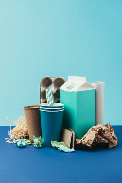 крупный план расположения картона и одноразового бумажного мусора на синем фоне
