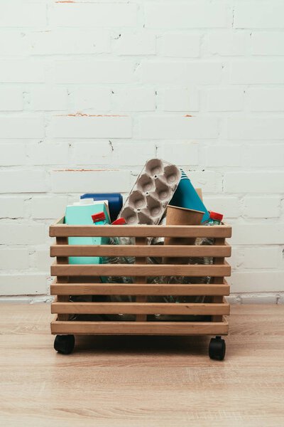 крупный план различных видов мусора в деревянной коробке с белой кирпичной стеной на заднем плане
 