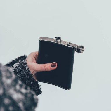 cropped shot of woman holding flask in hand on winter day