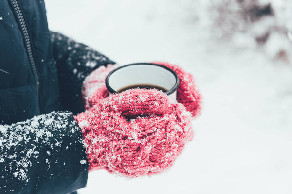 cropped shot of woman holding cup of tea in hands on winter day
