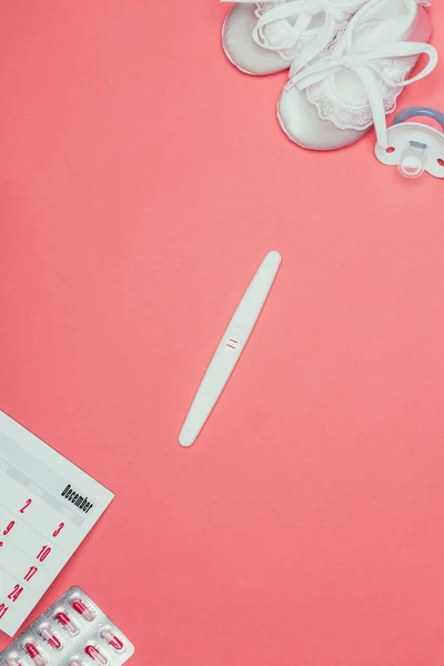 子供靴 避妊薬 おしゃぶり ピンクに分離された妊娠検査のトップ ビュー — ストック写真