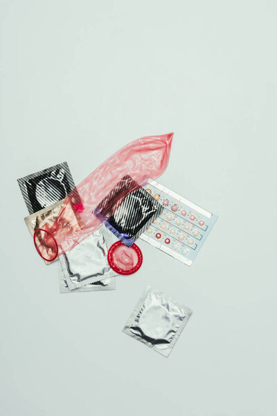 вид контрацептивных таблеток и презервативов, изолированных на сером
