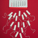 Vista superior de tampões menstruais arranjados e calendário isolado em vermelho