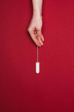 cropped shot of woman holding tampon in hand isolated on red  clipart