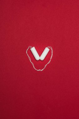 top view of arranged in heart menstrual tampons isolated on red clipart