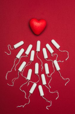 top view of arranged menstrual tampons and red heart isolated on red clipart