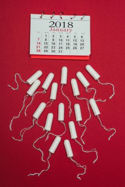 top view of arranged menstrual tampons and calendar isolated on red clipart