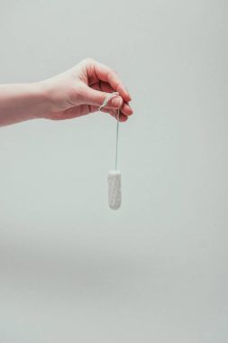 cropped shot of woman holding tampon in hand isolated on grey clipart