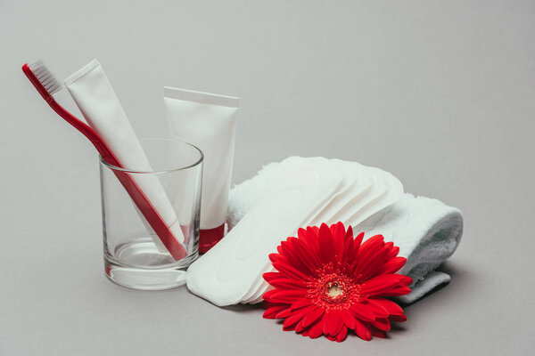 close up view of hygiene supplies, flower and towel isolated on grey