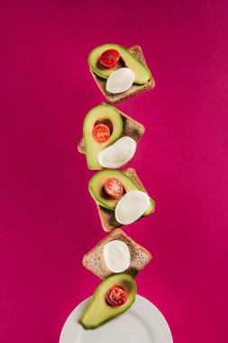 tost, avokado parçaları, mozzarella peyniri ve domates pink izole plaka üzerinde düşen görünümünü kapat