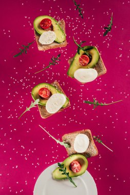 tost, avokado parçaları, mozzarella peyniri ve domates pink izole plaka üzerinde düşen görünümünü kapat