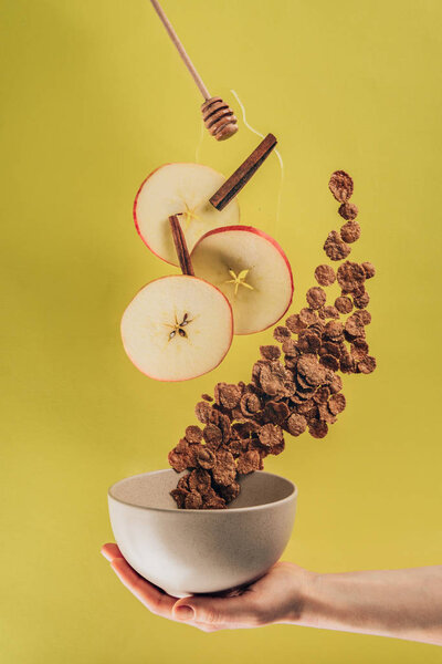 cropped shot of woman holding bowl with levitating breakfast