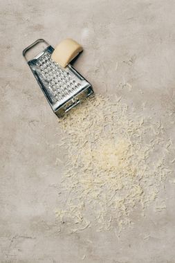 Grater and piece of cheese on light background clipart