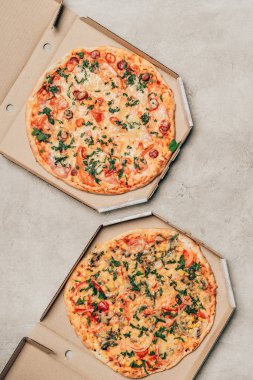 Italian pizzas in delivery boxes on light background clipart