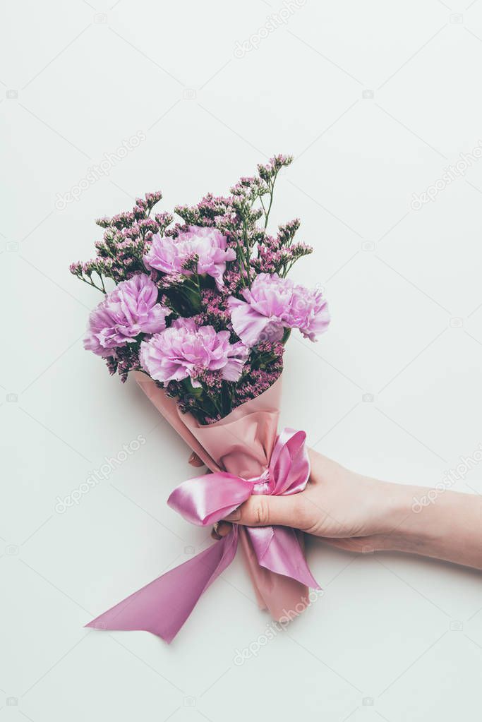 cropped shot of person holding beautiful elegant bouquet of tender purple flowers with ribbon isolated on grey