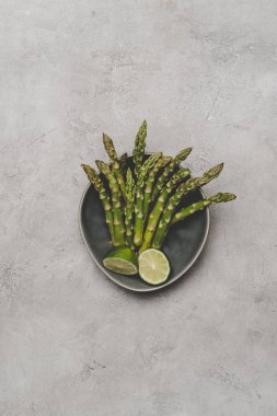 Grey tabağa dilimlenmiş limon ve taze sağlıklı kuşkonmaz Üstten Görünüm