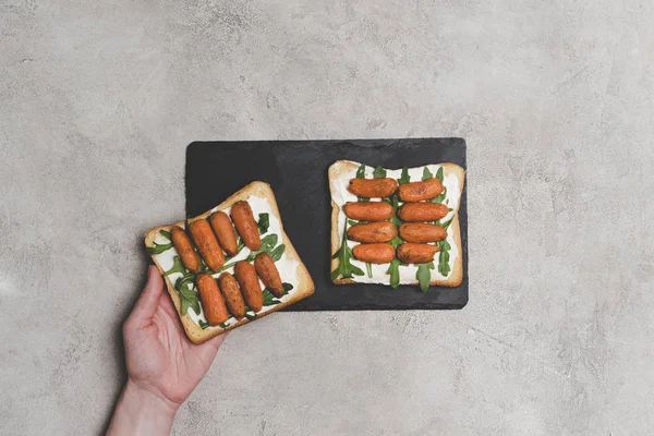 Abgeschnittene Aufnahme Menschlicher Hand Und Gesunde Sandwiches Mit Rucola Und — kostenloses Stockfoto