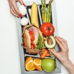 Oříznutý obraz žen užívajících potraviny ze zásobníku izolované na bílém