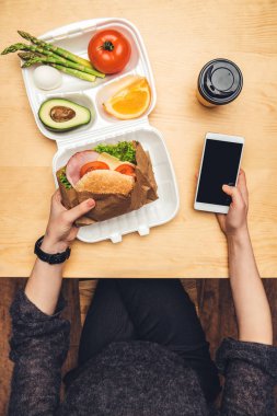 burger ve akıllı telefon elinde tutan kadının Resim kırpılmış