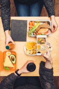 Tablo ve öğle yemeği alarak fotoğraf smartphone ile oturan kadın kırpılmış görüntü