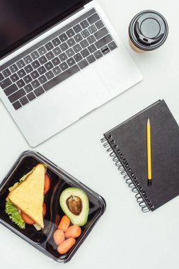 dizüstü bilgisayar ve gıda üzerinde beyaz izole öğle yemeği kutusu içinde üstten görünüm
