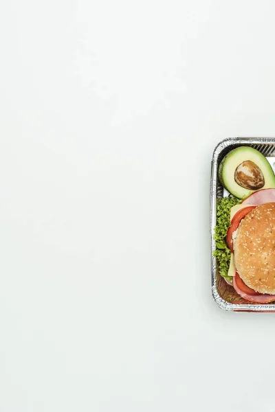 cropped image of burger with avocado in lunch box isolated on white