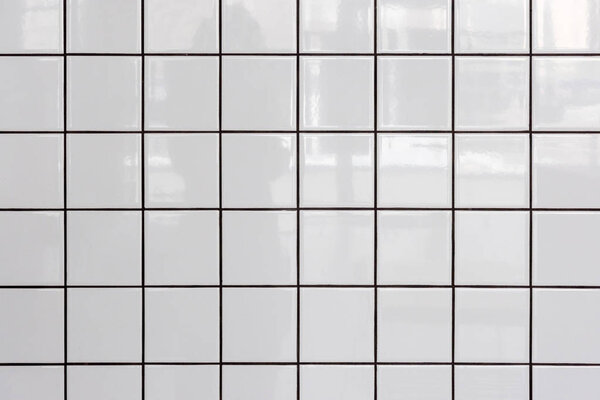 Wall of white glossy tiles with reflection