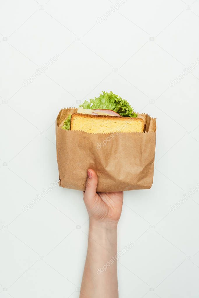 cropped image of woman holding sandwich in paper bag isolated on white