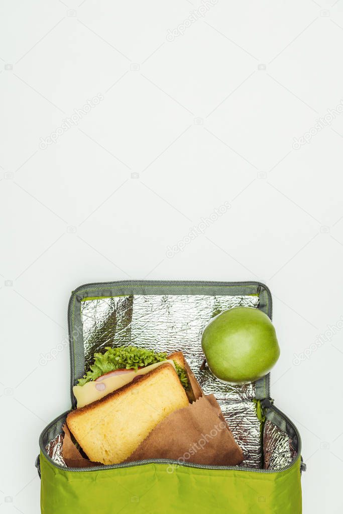 top view of sandwich and apple in lunch bag isolated on white