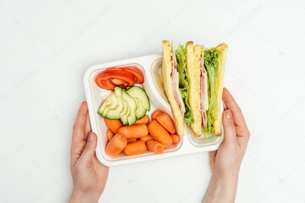 cropped image of woman holding lunch box with sandwiches isolated on white
