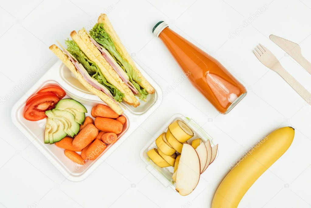 top view of sandwiches, fruits and vegetables in containers isolated on white