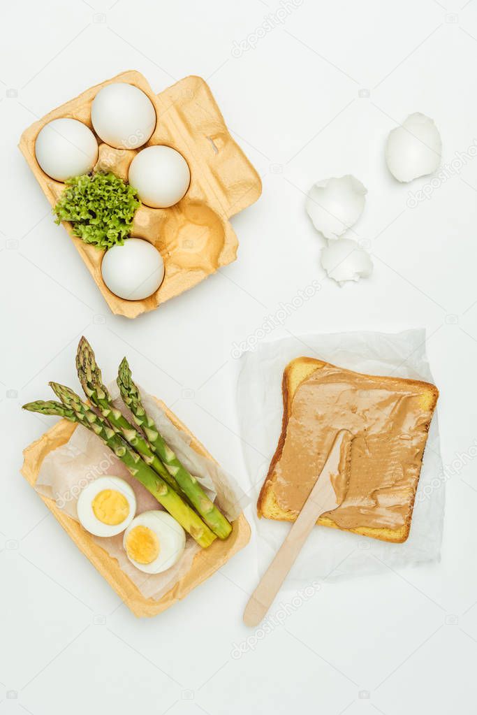 top view of bread with peanut butter and eggs on tray isolated on white