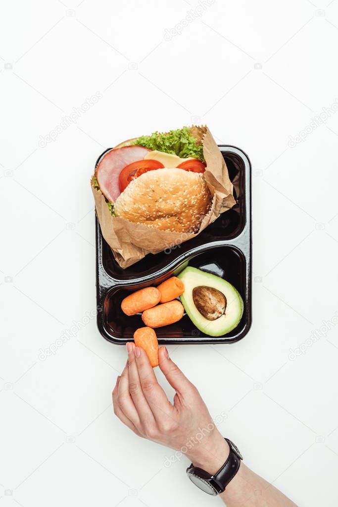 cropped image of woman taking carrot from take away container isolated on white